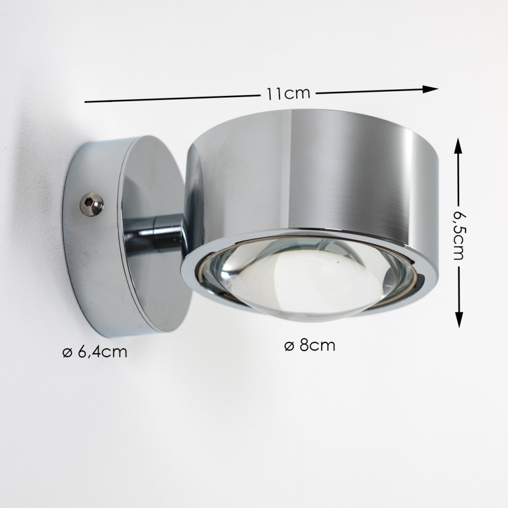 Eine verchromte Wandlampe. Abmessungen sind beschriftet: 11 cm, 6,5 cm, ø8 cm und ø6,4 cm. Sie befindet sich an einer weißen Wand.