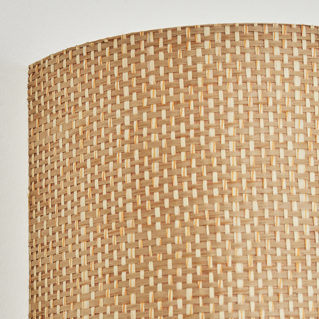 Nahaufnahme eines gewebten Lampenschirms. Er zeigt ein sich wiederholendes Muster aus rechteckigen Webarten in Beige und Creme.
