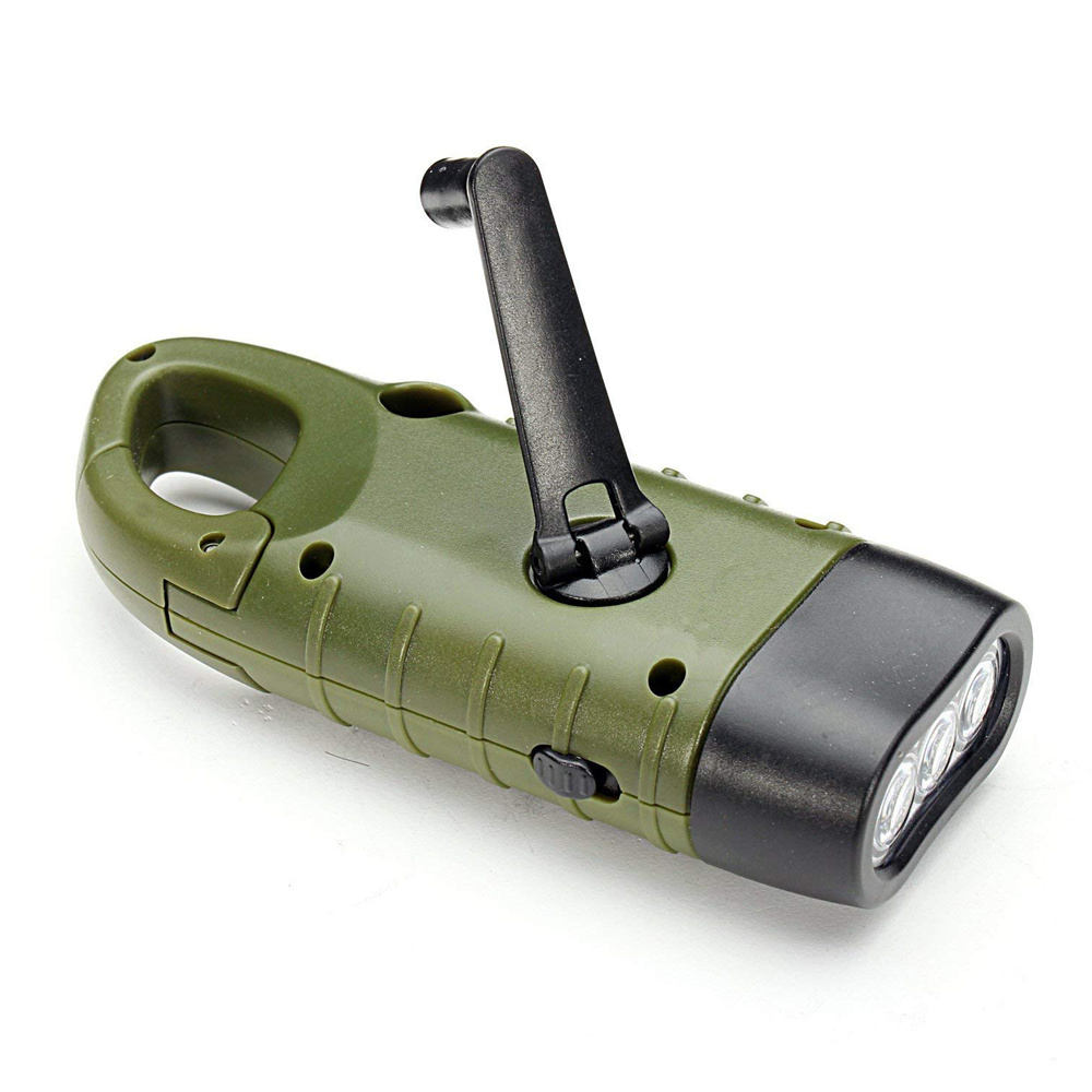 Eine olivgrüne Handkurbel-Taschenlampe. Sie hat einen schwarzen Griff und einen schwarzen Kopf mit drei LED-Leuchten. Sie liegt auf einer weißen Oberfläche.