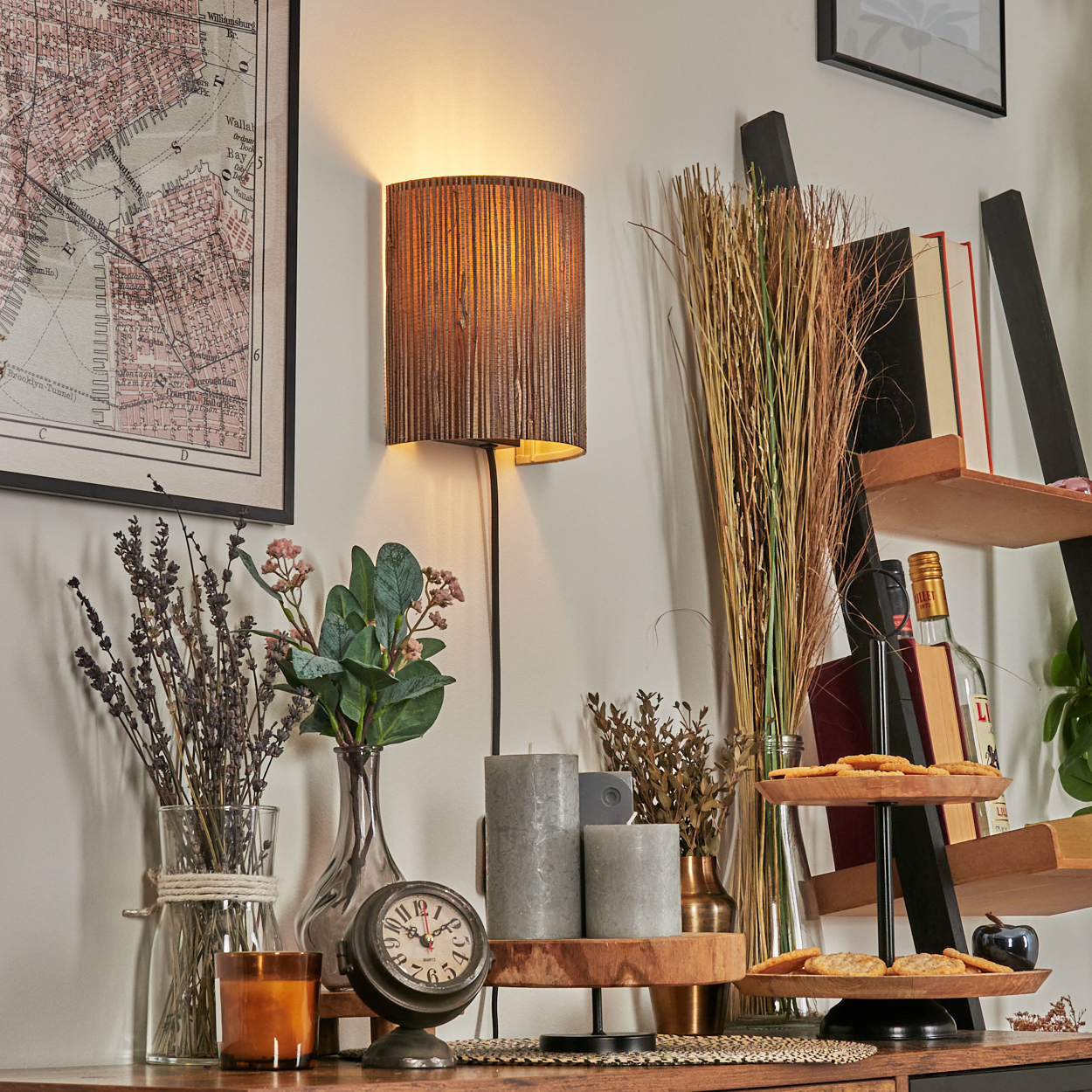 Eine Zimmerecke mit Karte, Lampe, Blumen, Uhr, Kerzen, Leiterregal mit Büchern und Keksen.