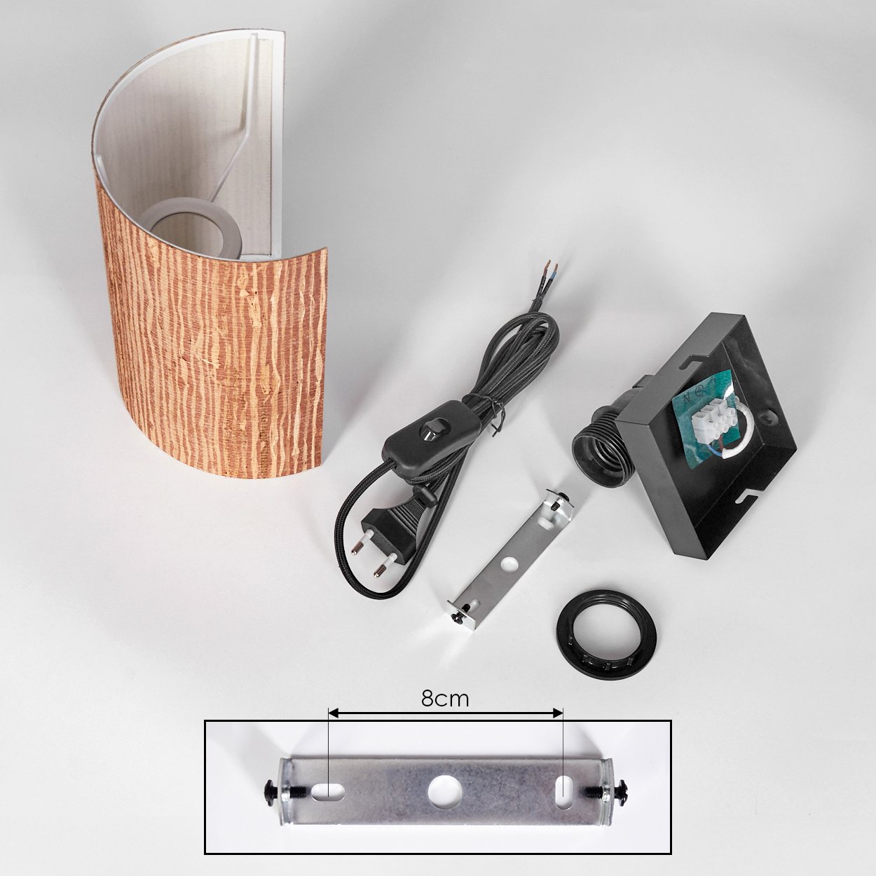 Eine zerlegte Lampe mit Lampenschirm, elektrischen Komponenten und einer Halterung. Teile sind auf weißer Oberfläche angeordnet.