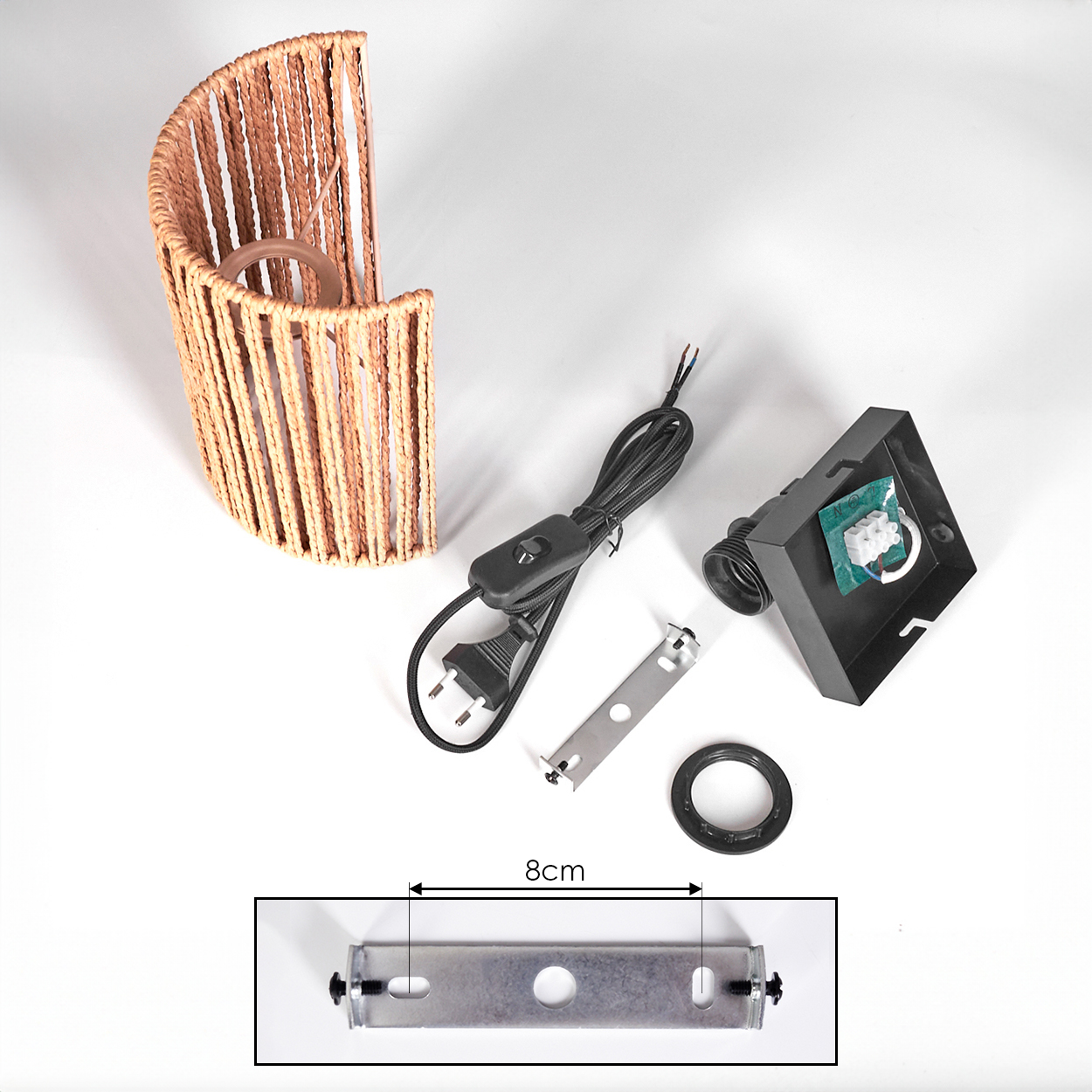 Eine zerlegte Lampenschirm aus Korbgeflecht mit elektrischen Komponenten, darunter ein Schalter, ein Stecker und eine Halterung, auf weißer Oberfläche.