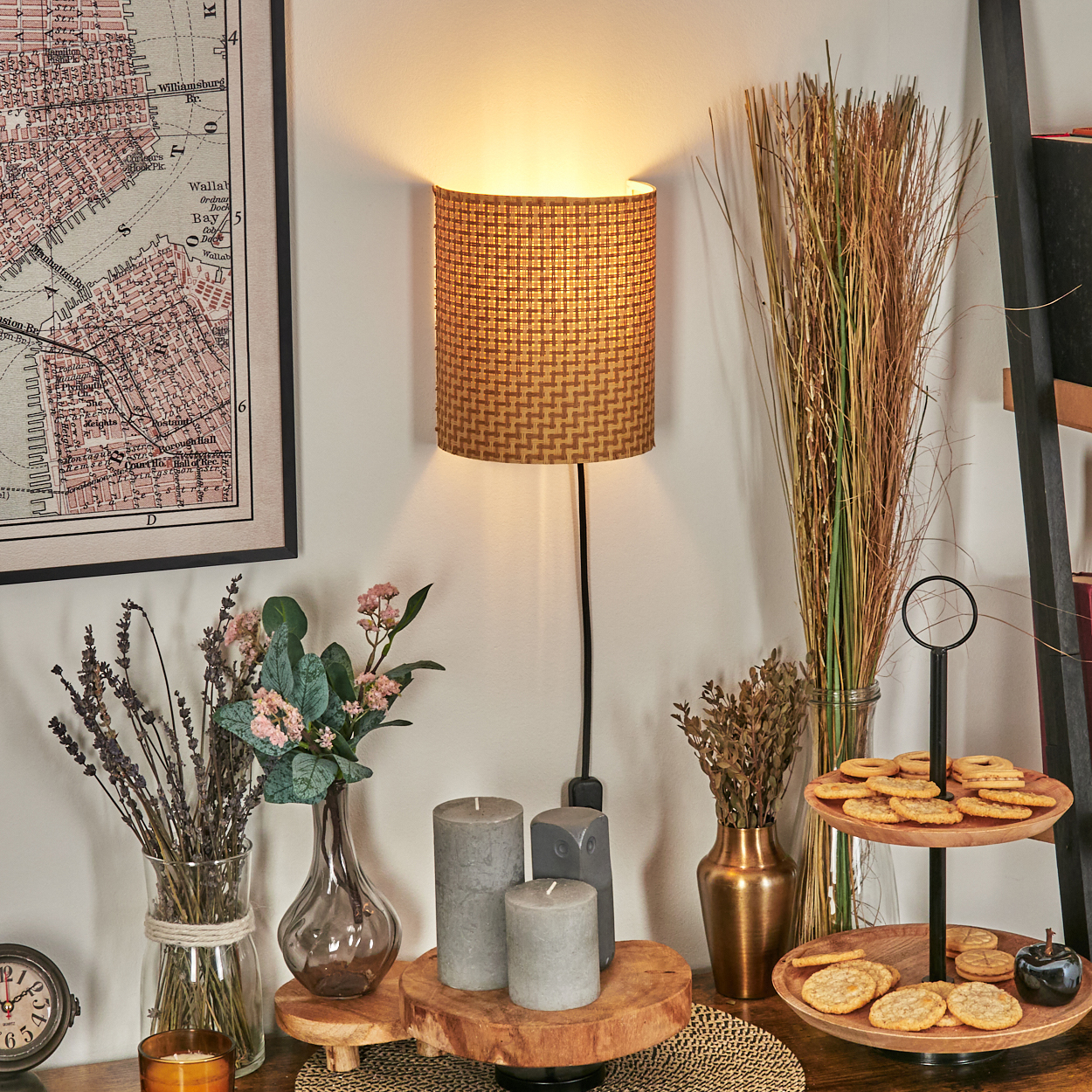 Eine beleuchtete, gemusterte Lampe hängt über einem Tisch mit Kerzen, Blumen, Keksen und einem Kartenaufdruck.