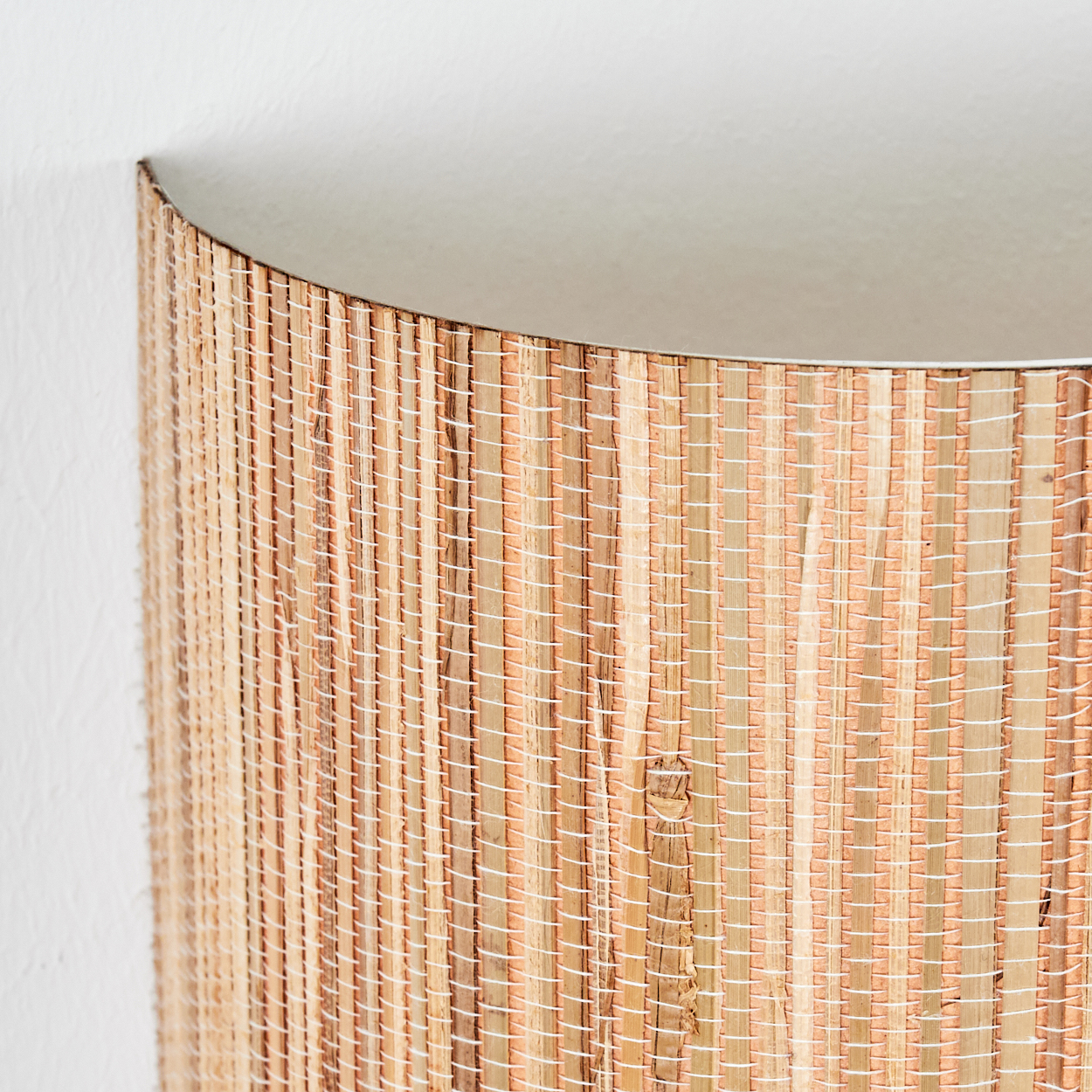 Nahaufnahme eines gewebten zylindrischen Objekts, möglicherweise einer Lampe. Es hat ein hellbraunes, hellbraunes und weißes Farbschema. Der Hintergrund ist weiß.
