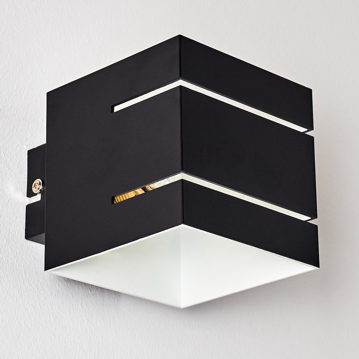 Eine moderne schwarz-weiße Wandleuchte. Es ist ein Würfeldesign mit weißem Innenraum und einem metallisch aussehenden Akzent an einer Wand.