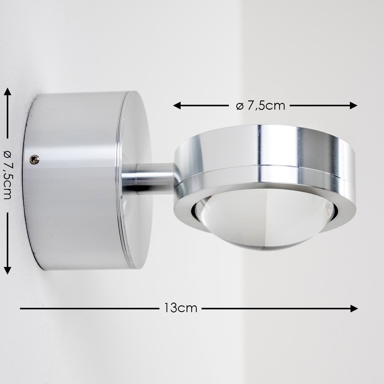 Eine moderne, verchromte Wandlampe mit kugelförmigem Licht, an einer weißen Wand montiert. Abmessungen sind angegeben.