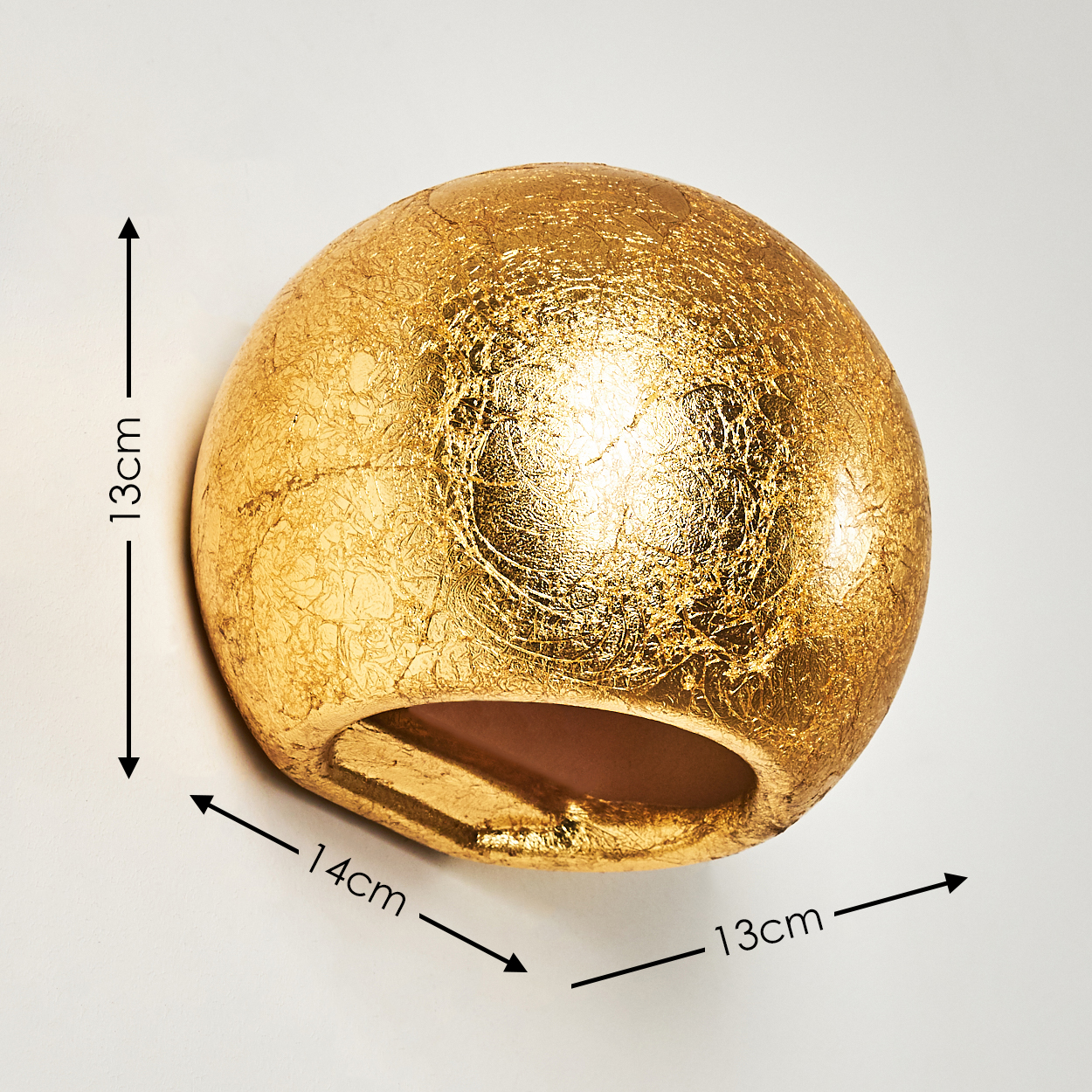 Eine goldene, kugelförmige Wandleuchte. Die Maße sind 13 cm, 14 cm und 13 cm. Sie hat eine raue Textur und ist an einer weißen Wand befestigt.