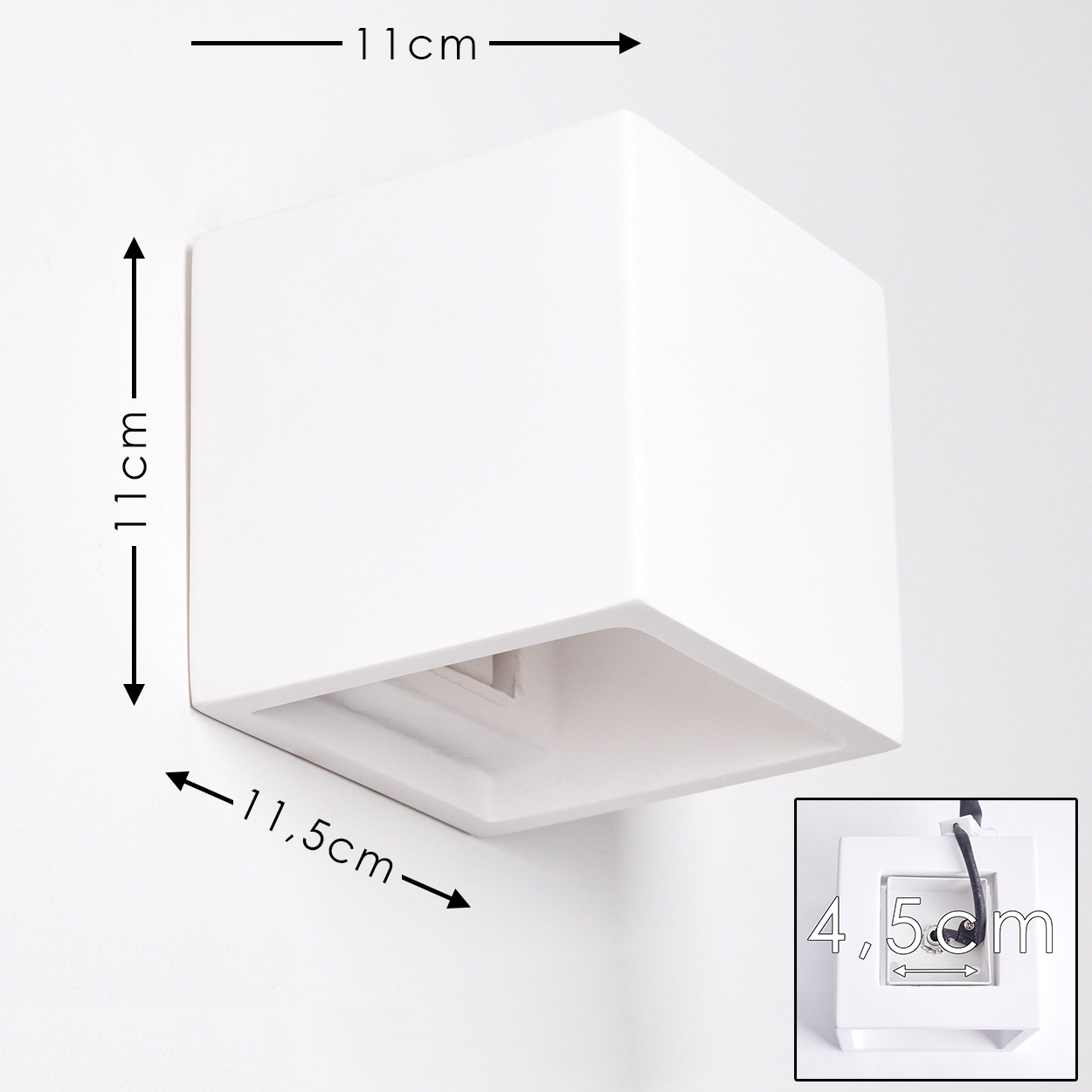 Eine weiße quadratische Lampe an einer weißen Wand. Abmessungen: 11cm x 11cm x 11,5cm. Ein kleinerer Ausschnitt zeigt eine Steckdose.