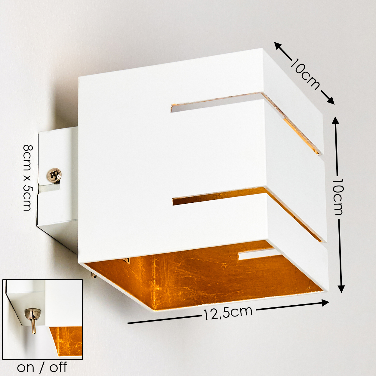 Eine weiße, quadratische Wandleuchte mit goldfarbenem Innenraum. Sie hat Aussparungen und ist an einer weißen Wand befestigt.