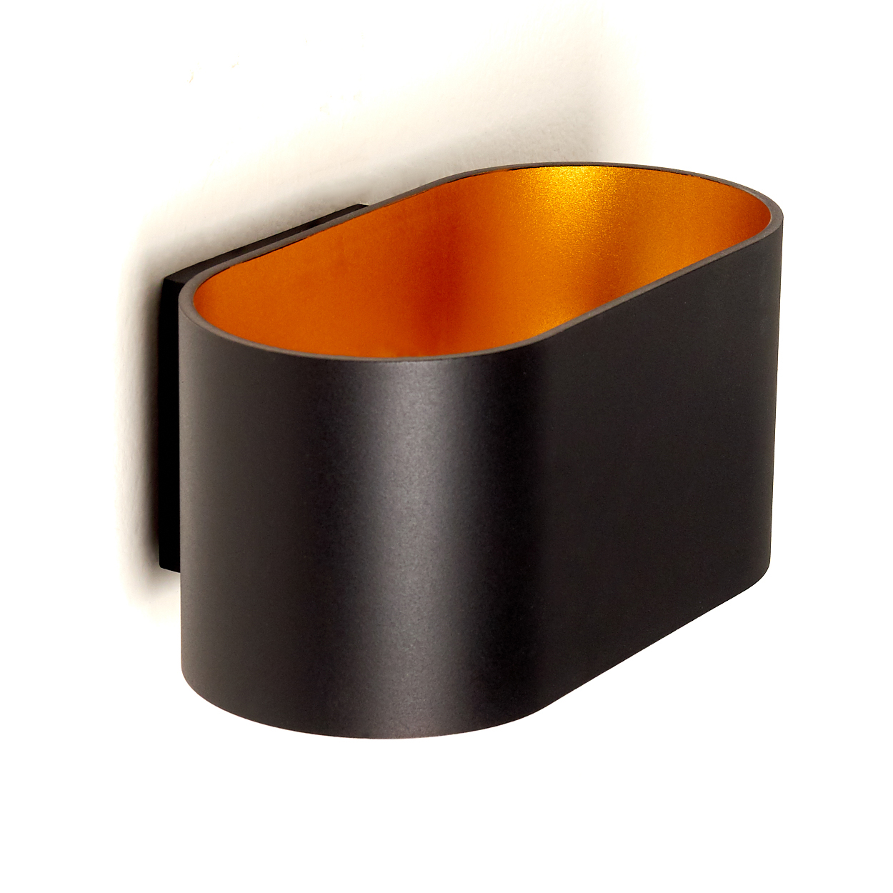 Eine moderne schwarze Wandleuchte mit goldener Innenseite ist an einer weißen Wand montiert. Die Lampe hat eine ovale Form.