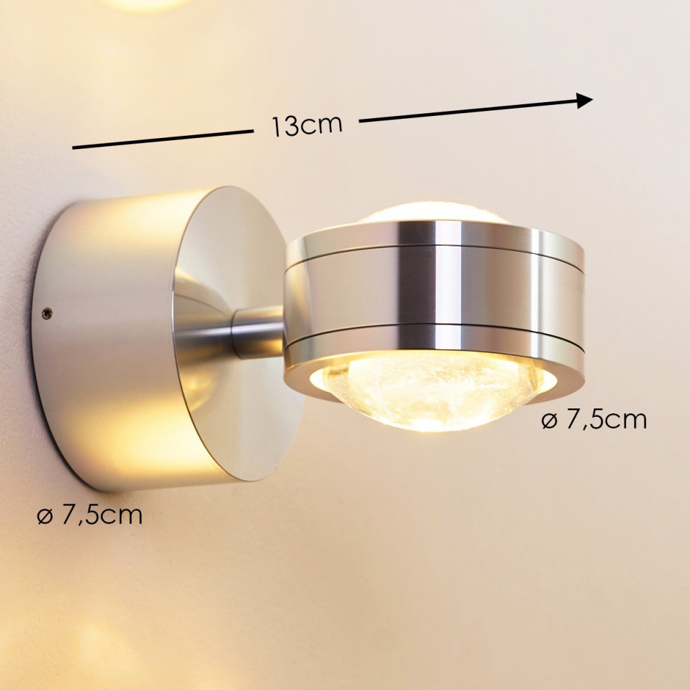 Eine moderne silberne Wandleuchte mit rundem Sockel und zylindrischem Kopf. Der Kopf hat eine Glaskugel, die Licht aussendet. Abmessungen sind angegeben.