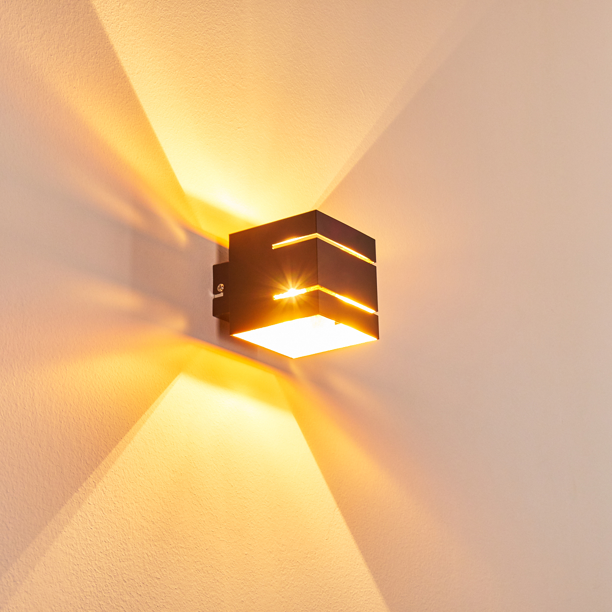 Eine moderne schwarze Wandleuchte wirft helles Licht und Schatten auf eine beige Wand.