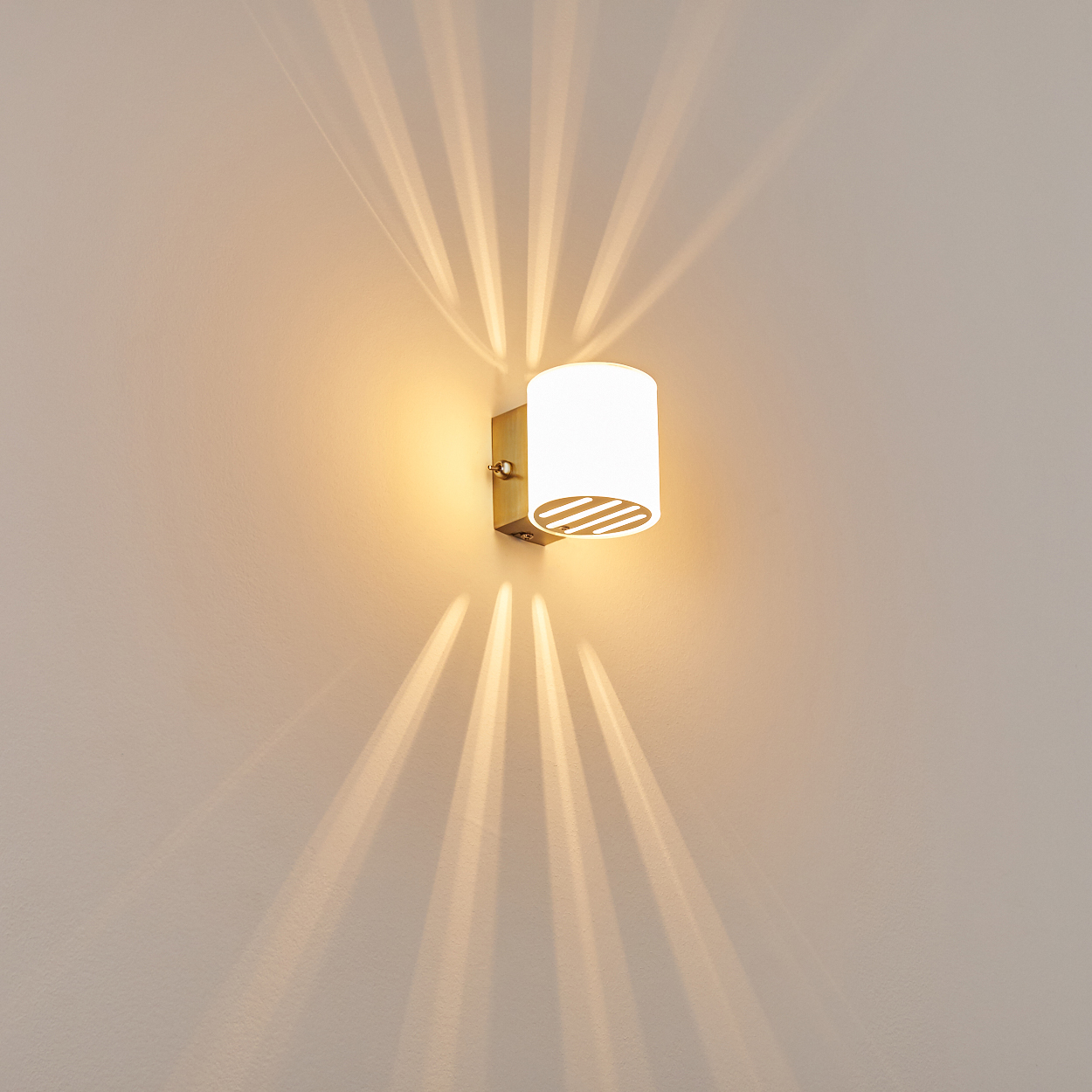 Eine Wandleuchte mit zylindrischem Schirm wirft Licht und Schatten auf eine beige Wand.