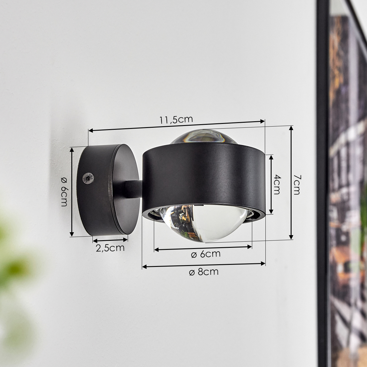 Schwarze Wandleuchte mit Maßangaben. Sie hat ein abgerundetes Design mit Glaskugel und metallischem Rundsockel.