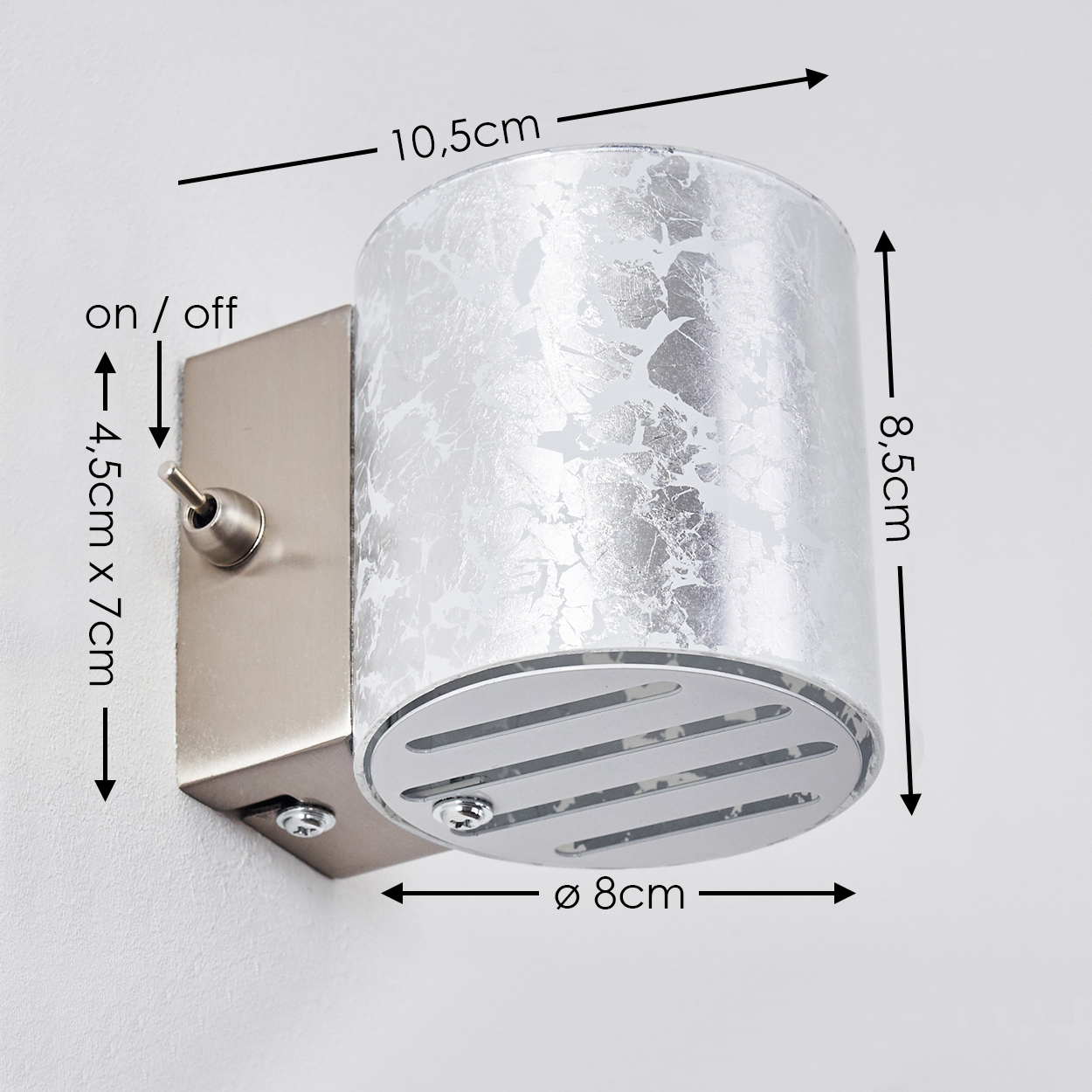 Eine silberne Wandlampe mit zylindrischem Lampenschirm. Sie hat einen Metallsockel mit Ein-/Ausschalter. Abmessungen sind angegeben.