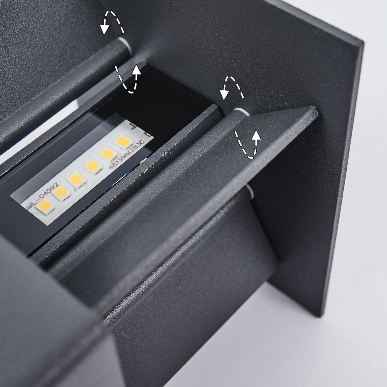 Nahaufnahme einer schwarzen, modernen Außenleuchte mit LED-Streifen. Die Leuchte hat abgewinkelte Lamellen und ist auf weißem Untergrund montiert.