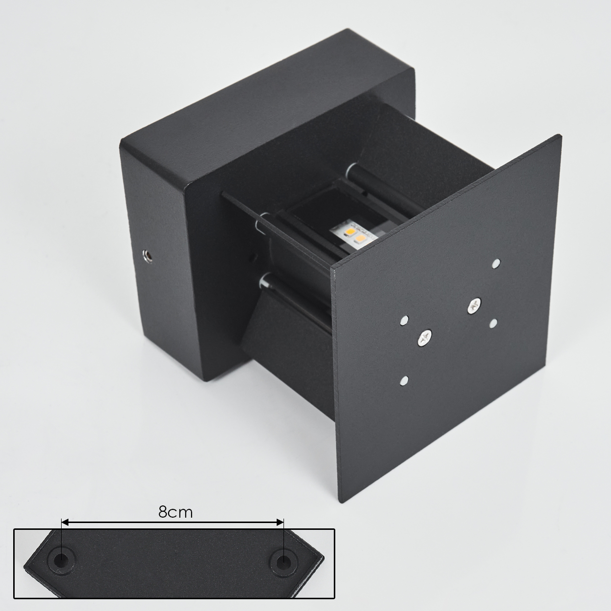 Eine schwarze, moderne Wandleuchte wird auf einer weißen Oberfläche dargestellt. Die Lampe hat einen rechteckigen Körper und eine quadratische Frontplatte.