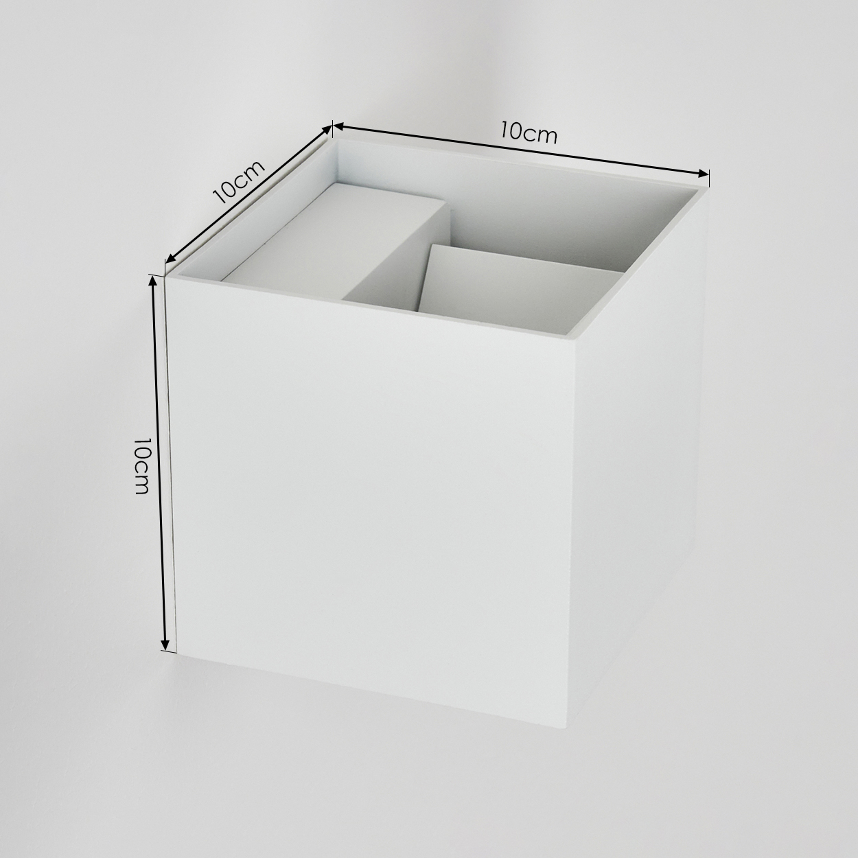 Ein weißer quadratischer Kasten mit inneren Unterteilungen. Seiten mit 10 cm markiert. Der Kasten steht auf weißem Hintergrund.