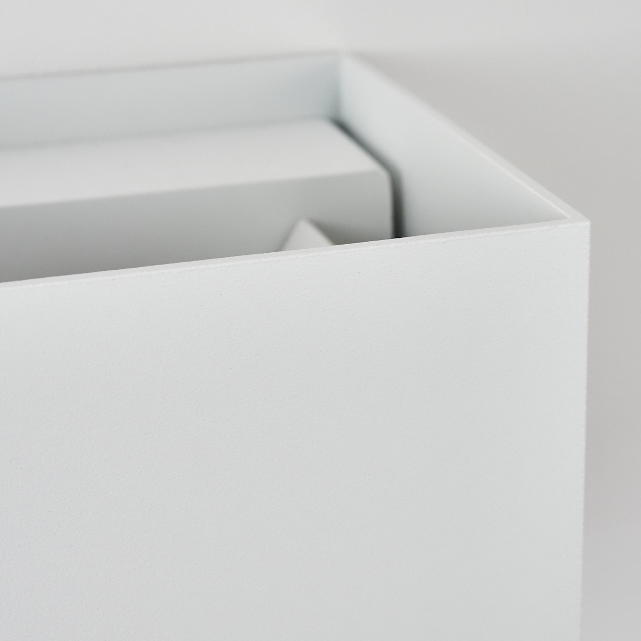 Nahaufnahme einer weißen Box mit Deckel, die eine kleinere Box im Inneren zeigt. Der Hintergrund ist weiß.