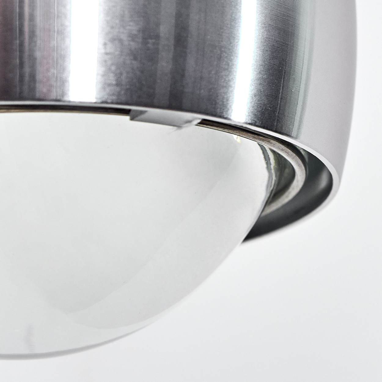 Nahaufnahme einer Metallleuchte mit Glaskugel. Die Leuchte ist silberfarben, der Hintergrund ist weiß.