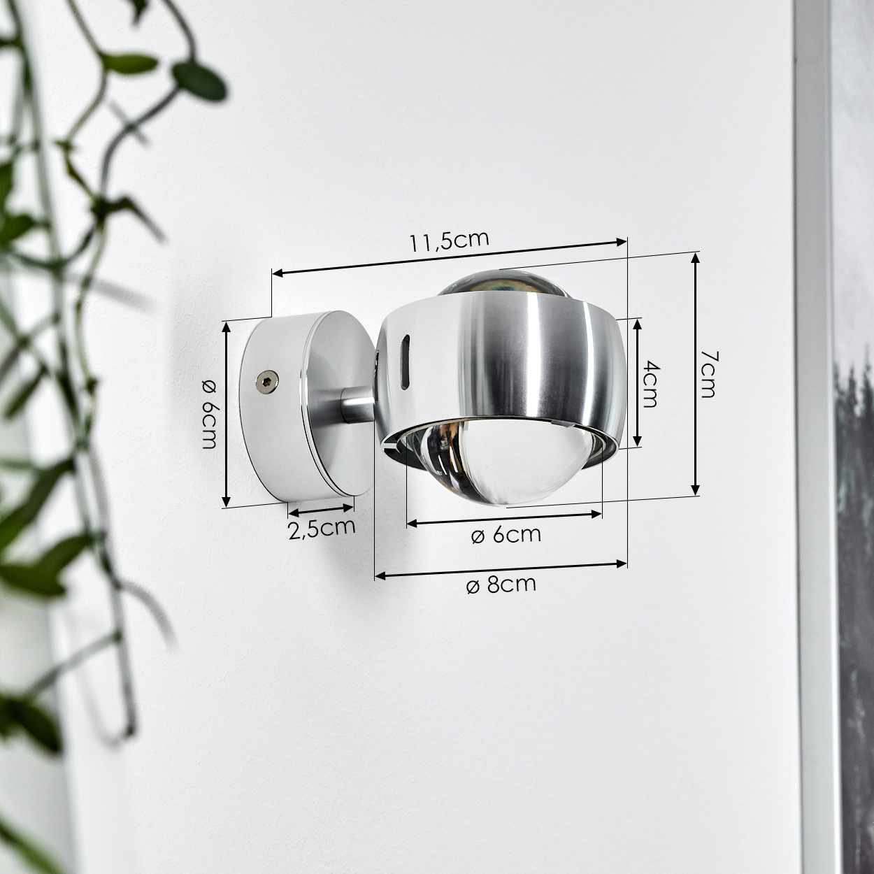 Eine metallische Wandleuchte mit klarem Glasschirm, an einer weißen Wand montiert. Abmessungen sind mit Pfeilen und Zahlen angegeben.