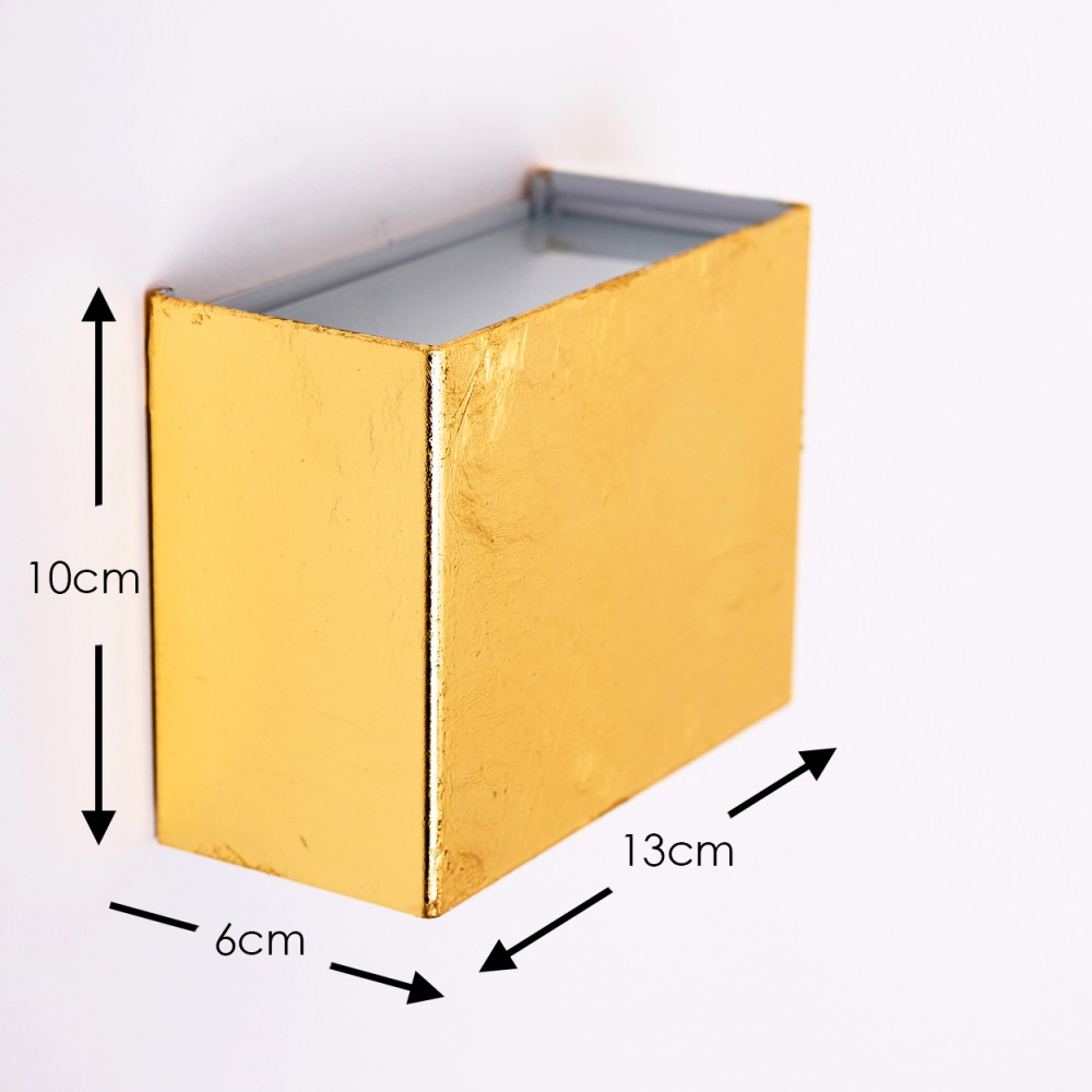Ein goldener rechteckiger Kasten ist an einer weißen Wand befestigt. Abmessungen sind angegeben: 10cm Höhe, 13cm Breite und 6cm Tiefe.