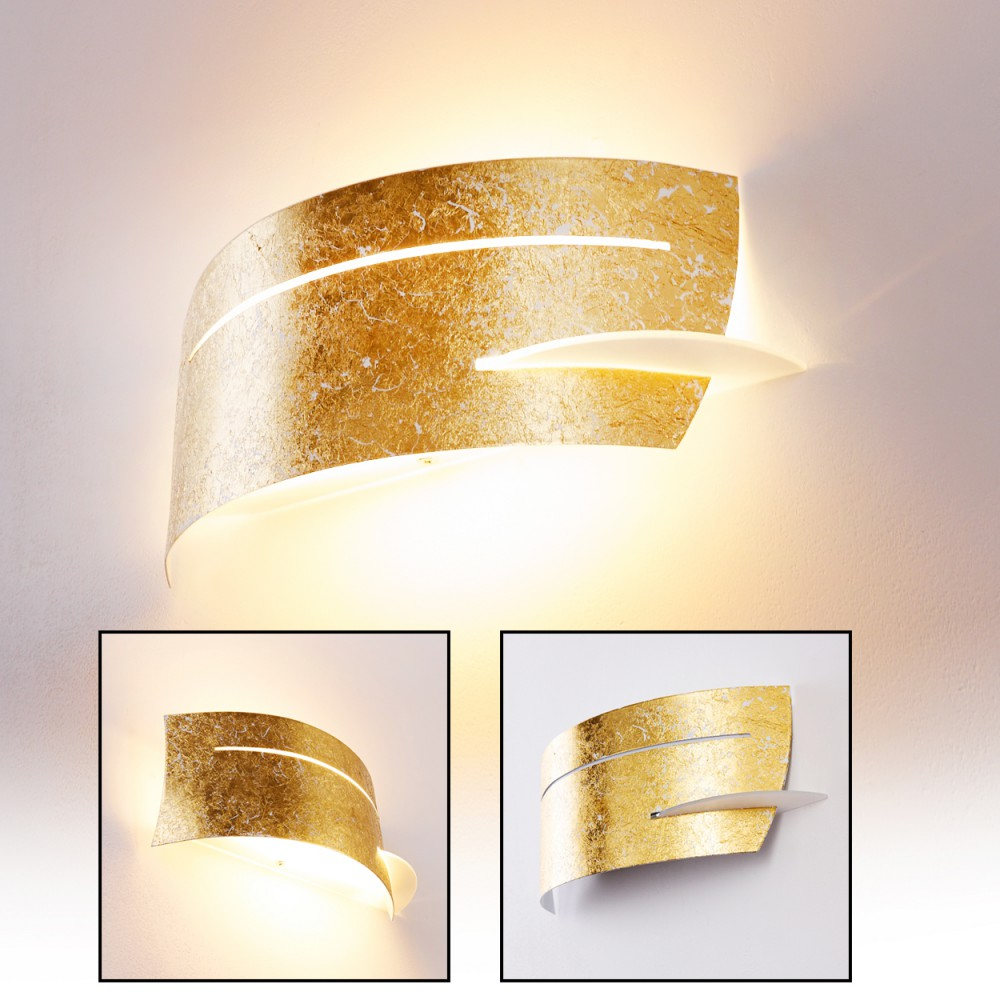 Eine goldene Wandleuchte mit geschwungenem Design. Sie hat eine blattartige Form mit weißem Akzent. Sie ist an einer weißen Wand befestigt.
