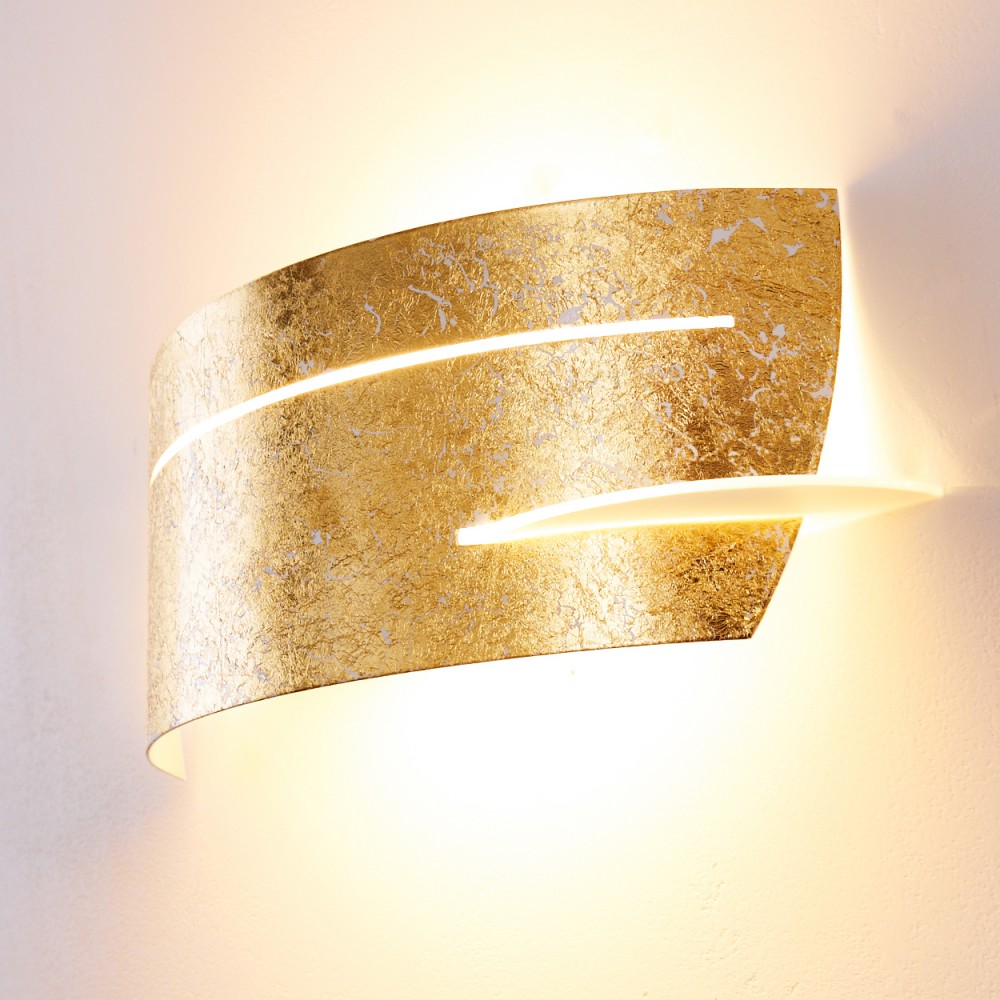 Eine goldene Wandlampe mit strukturierter Oberfläche und zwei horizontalen Lichtstreifen. Sie wirft einen warmen Schein an eine weiße Wand.