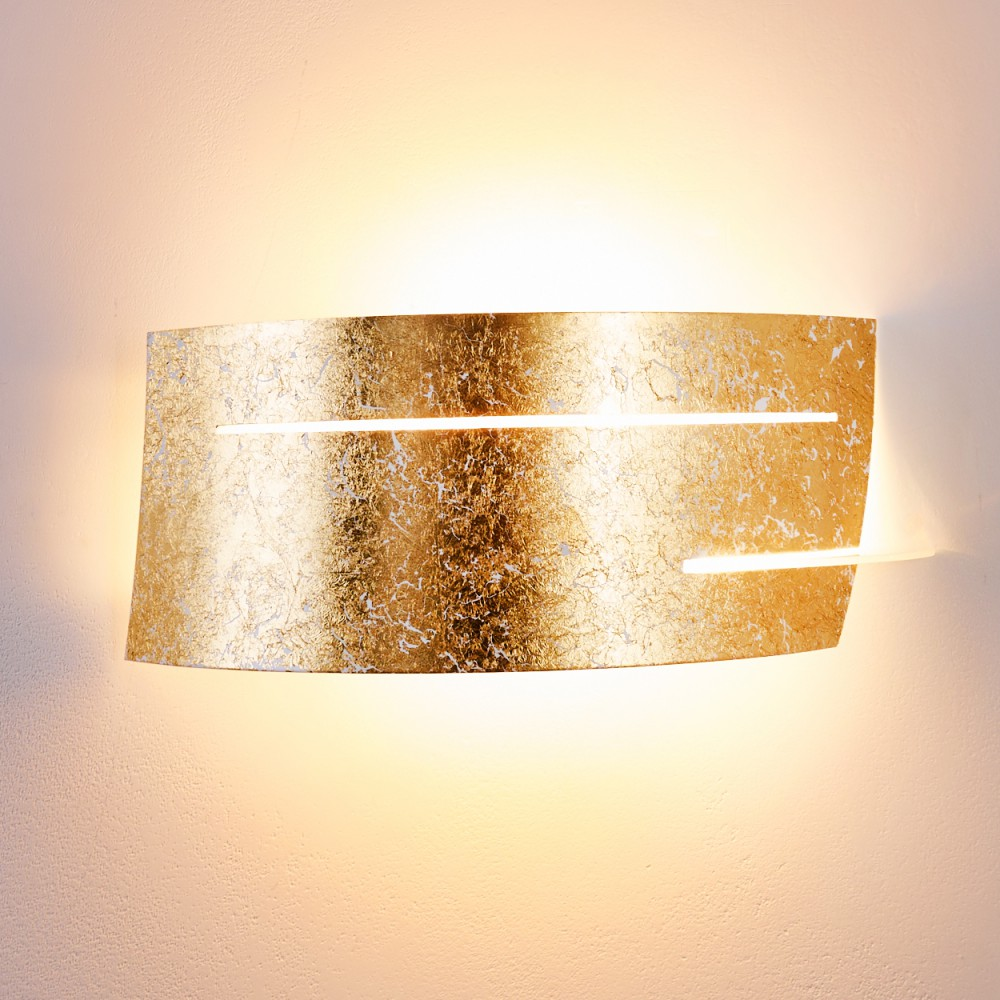 Eine goldene Wandlampe mit strukturierter Oberfläche, die warmes Licht ausstrahlt. Die Lampe ist an einer weißen Wand montiert.