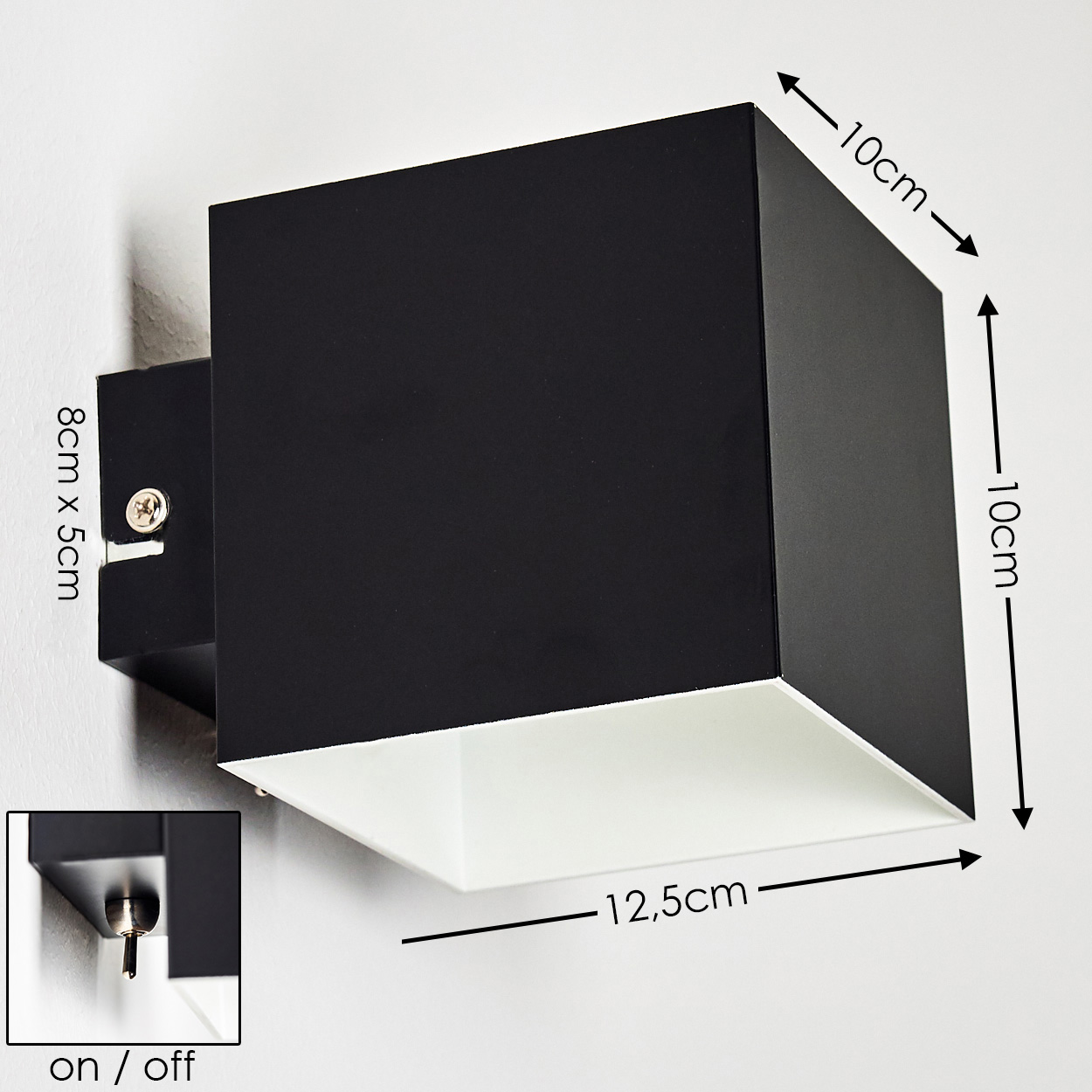 Schwarze quadratische Wandleuchte. Abmessungen sind beschriftet. Ein/Aus-Schalter ist abgebildet. Lampe hat einen weißen Innenraum. An einer weißen Wand montiert.