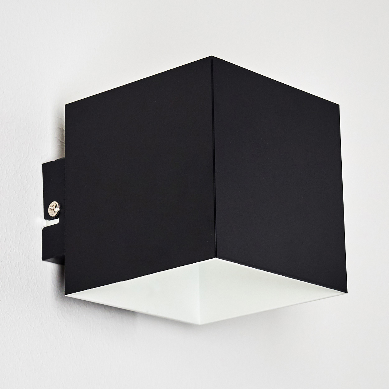 Eine moderne, schwarze, quadratische Wandleuchte ist an einer weißen Wand montiert. Die Lampe hat ein weißes Innere und ein schwarzes Äußeres.