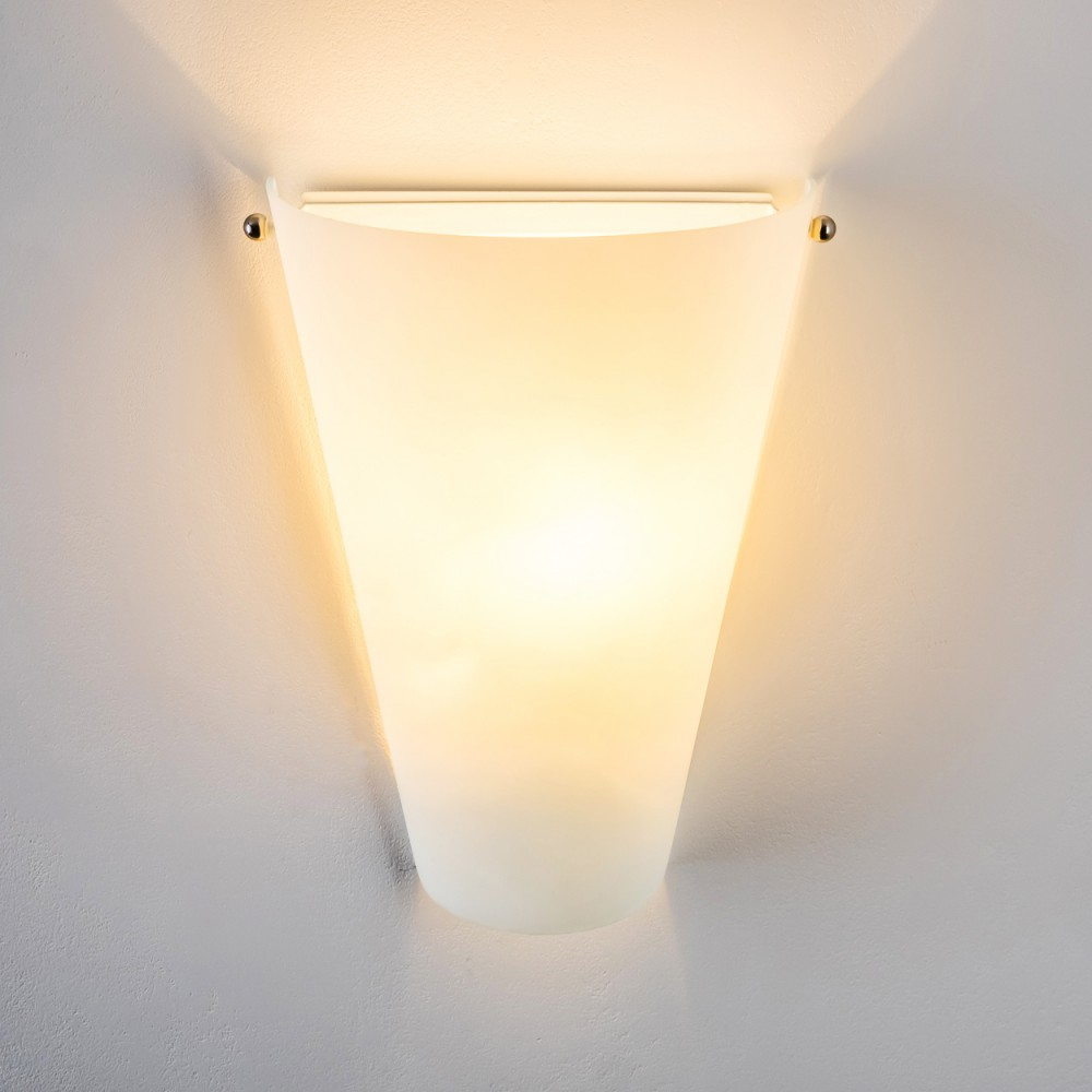 Eine weiße, konische Wandleuchte ist an einer weißen Wand befestigt. Sie strahlt ein weiches, warmes Licht aus. Der Hintergrund ist eine weiße Wand.