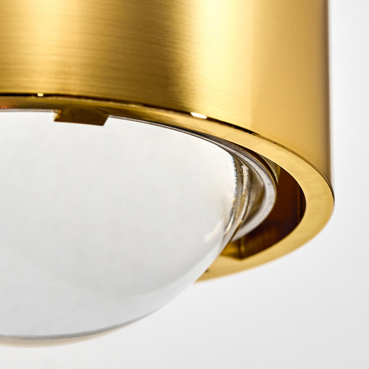 Nahaufnahme einer Messinglampe. Ein klarer Glaskolben ist teilweise von der Messinghalterung umschlossen, vor weißem Hintergrund.