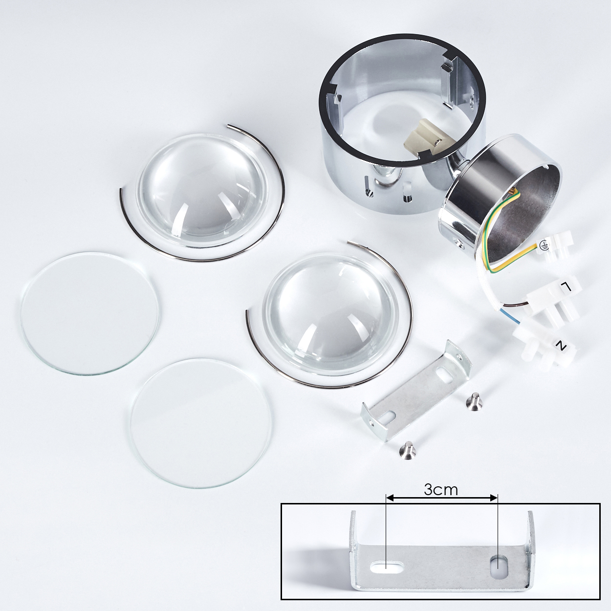 Zerlegte Lampenteile auf weißem Hintergrund. Enthält Glaslinsen, Metallgehäuse, Verdrahtung, Montagehalterung und Schrauben. Ein 3cm Lineal ist vorhanden.