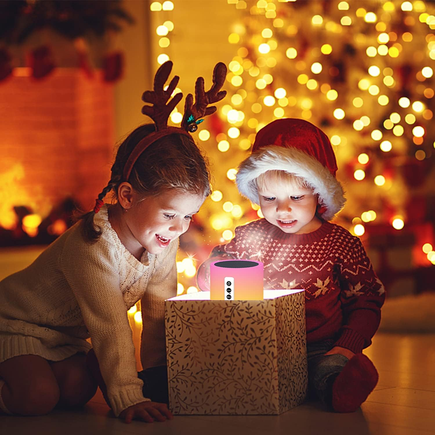 Zwei Kinder öffnen an Weihnachten eine leuchtende Geschenkbox. Eines trägt ein Rentiergeweih, das andere einen Weihnachtsmütze, umgeben von Lichtern.