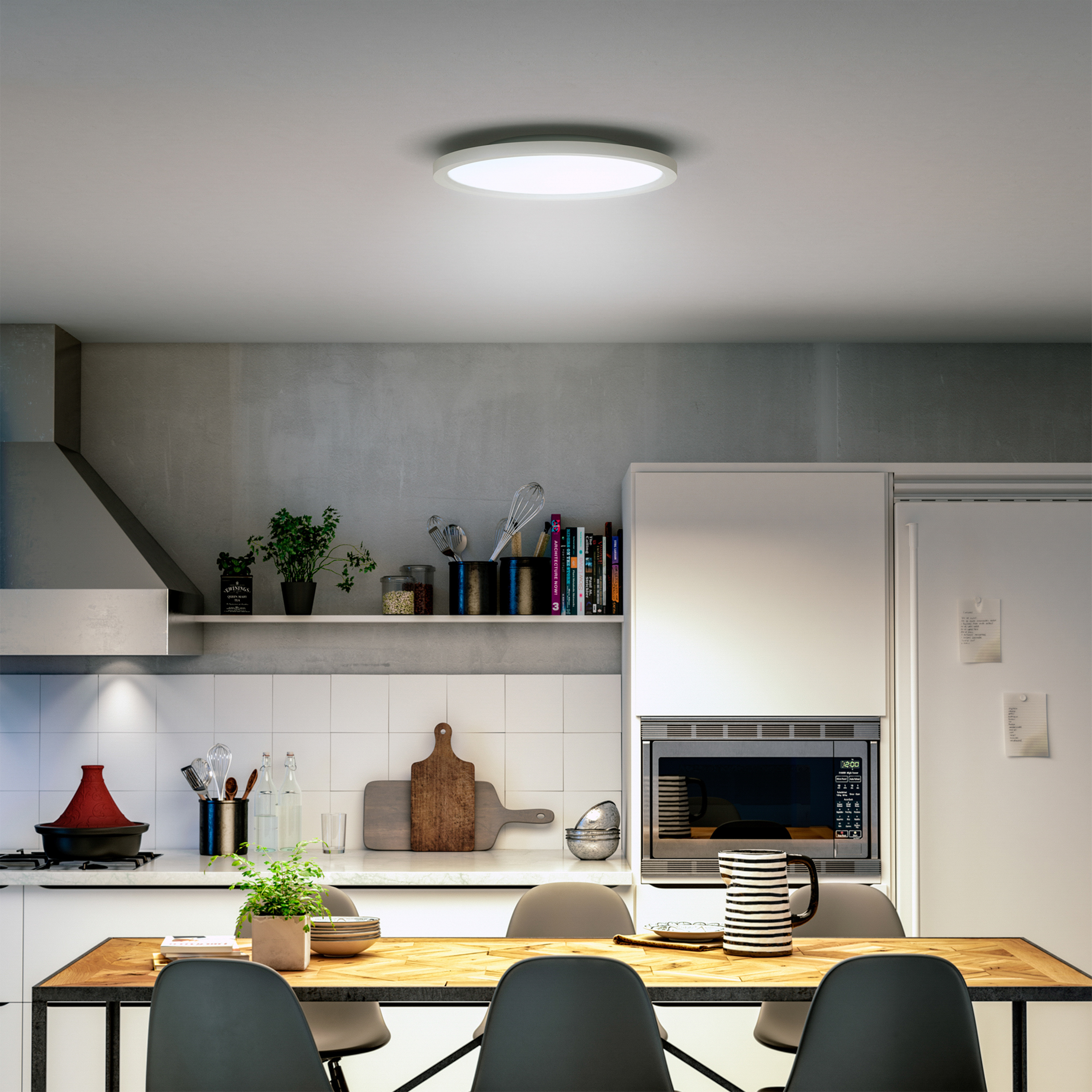 Une scène de cuisine avec une table à manger, des chaises, un micro-ondes et des plantes. Une lampe de plafond ronde est au-dessus.
