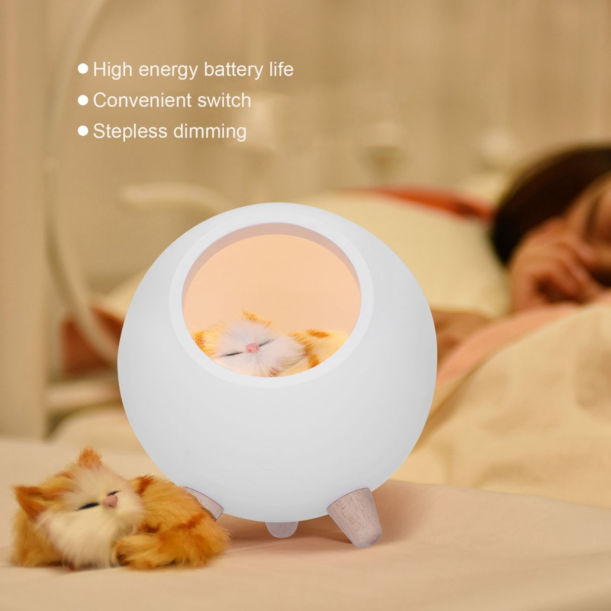 Eine weiße, runde Lampe mit einer schlafenden Katze im Inneren. Ein weiteres Katzenspielzeug befindet sich in der Nähe der Lampe. Eine Person ist im Hintergrund unscharf.
