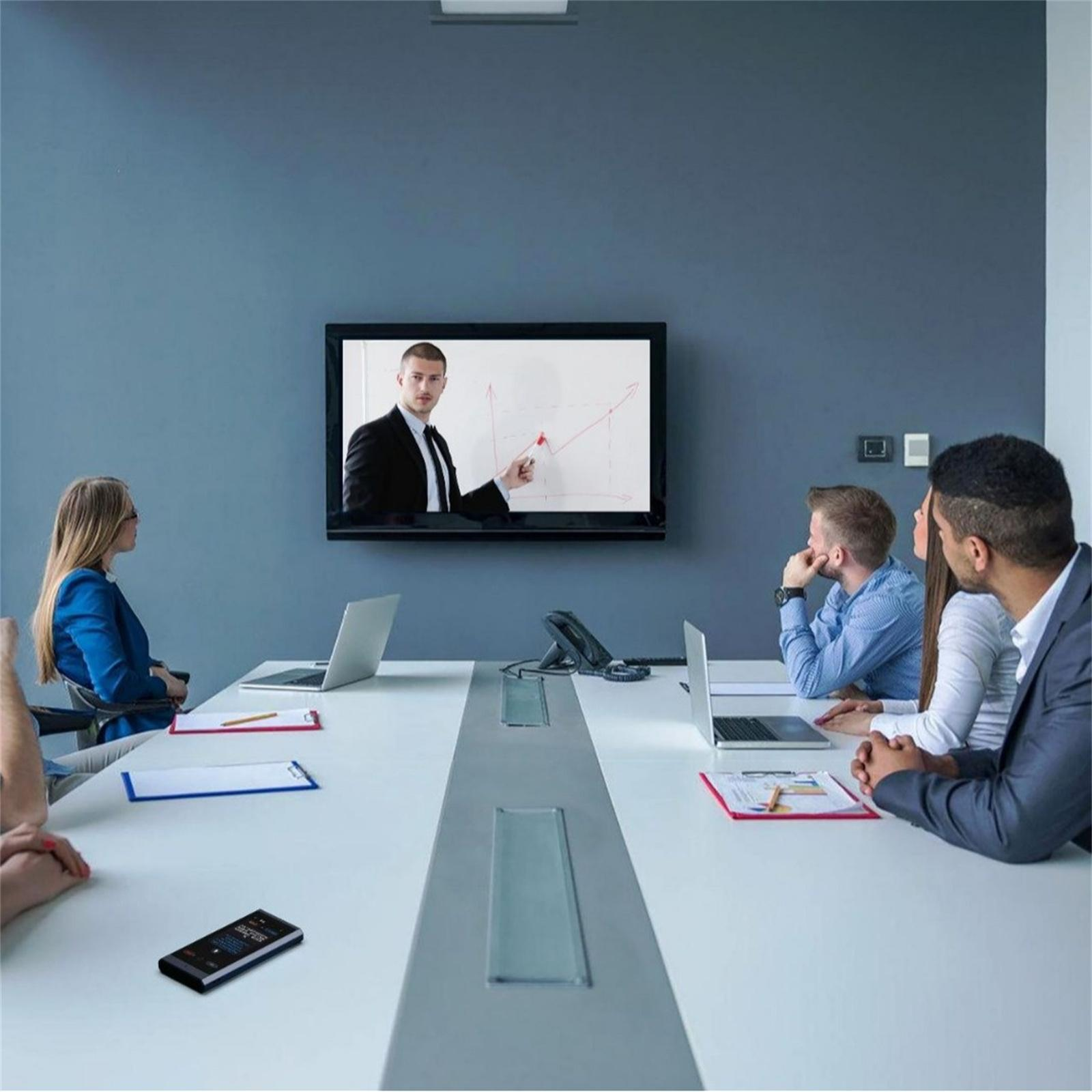 Ein Geschäftstreffen mit einer Videopräsentation. Personen sitzen um einen Tisch und schauen auf einen Bildschirm.