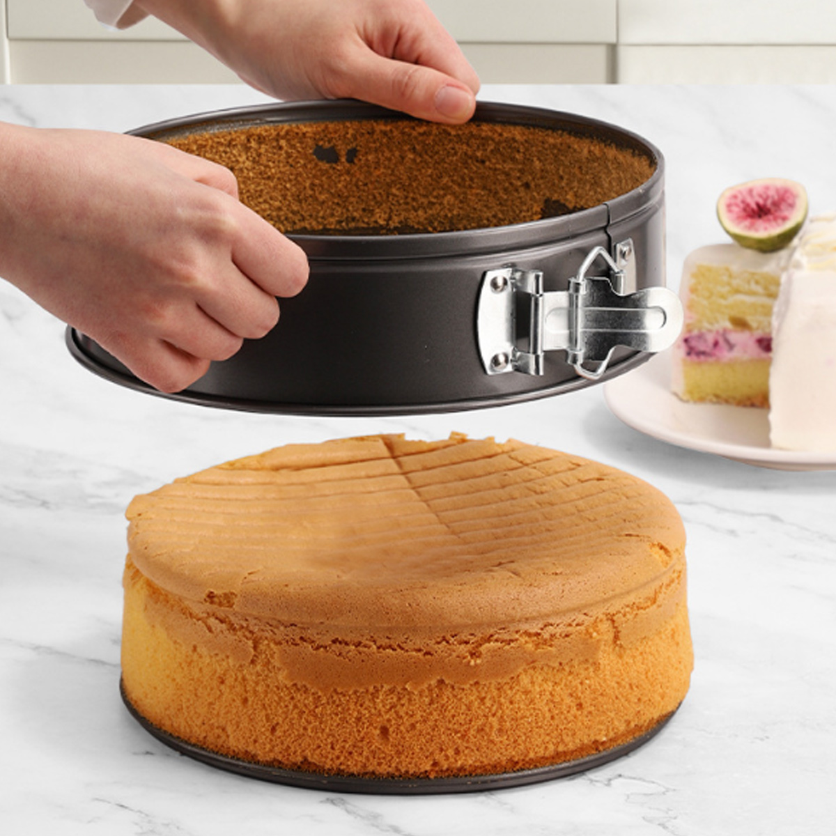 Hände halten eine Kuchenform über einem gebackenen Kuchen. Kuchenstücke mit Sahne und einer Feige sind im Hintergrund.