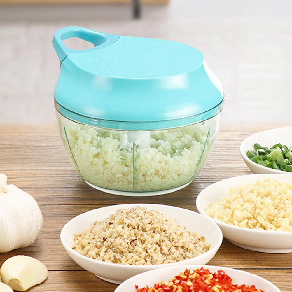 Ein manueller Zerkleinerer mit gehackten Zutaten in der Schüssel. Kleine Schalen enthalten gehackten Knoblauch, Nüsse, grüne Zwiebeln und rote Paprika.