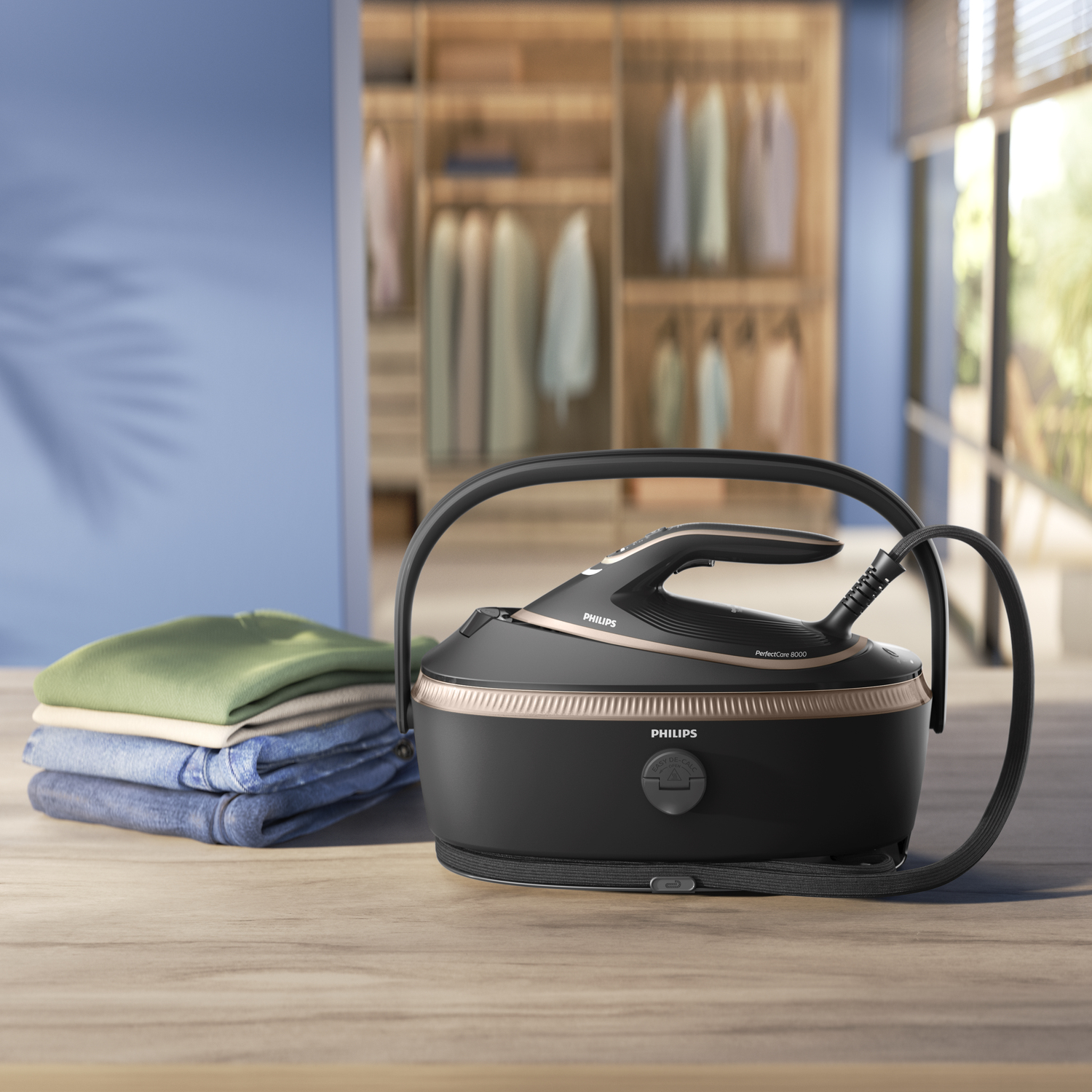 Ein schwarzes Philips-Bügeleisen steht auf einem Holztisch neben gefalteter Kleidung. Im Hintergrund ein Kleiderschrank.