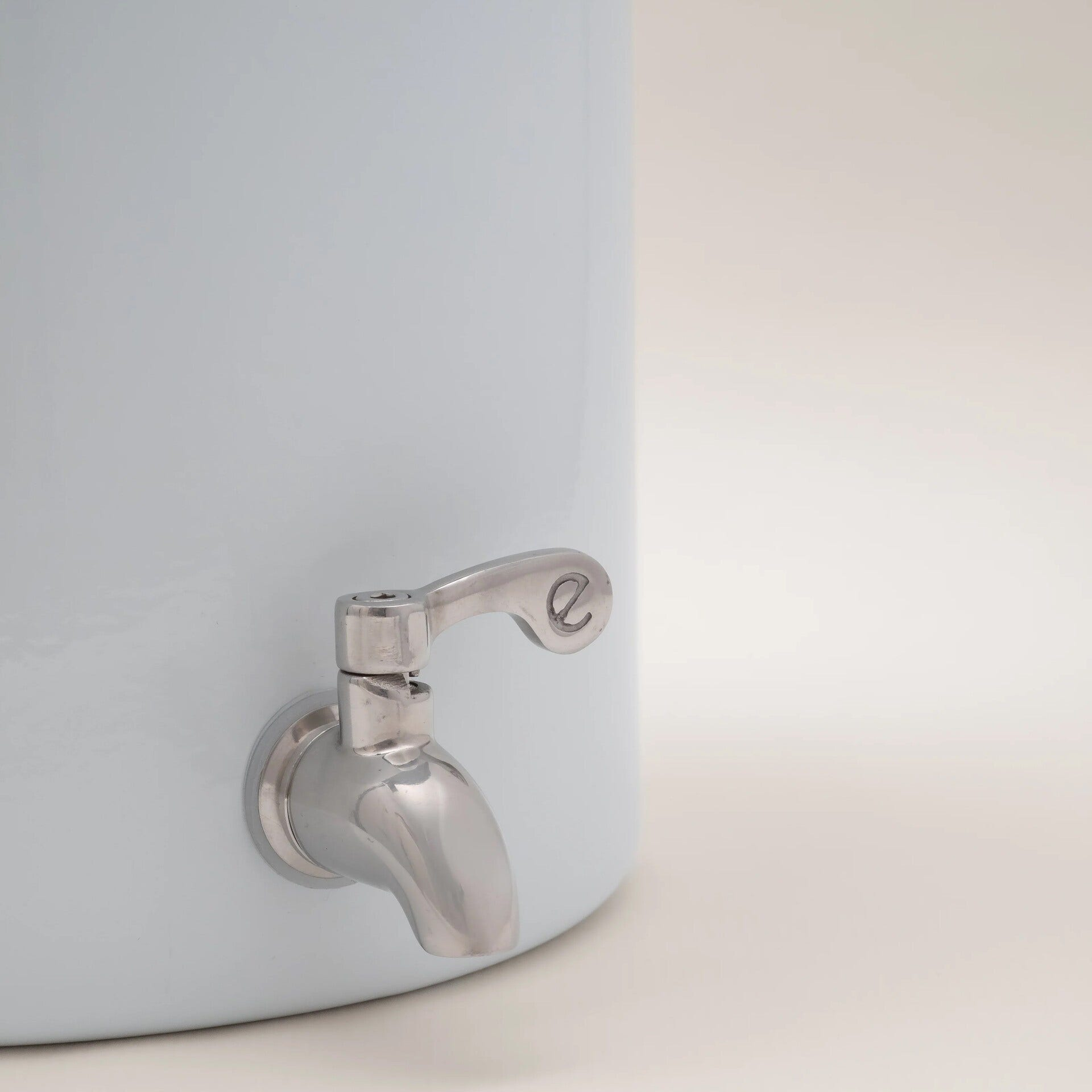 Un primo piano di un distributore d'acqua azzurro con un rubinetto d'argento su sfondo bianco.