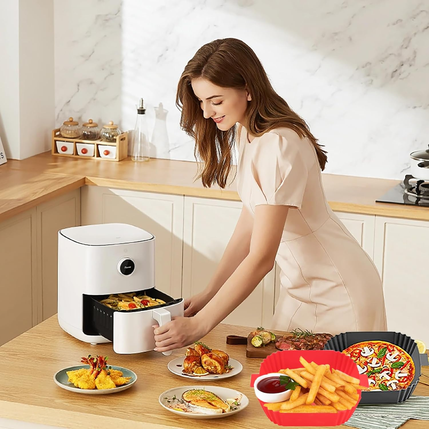 Eine Frau in einer Küche mit einer Heißluftfritteuse, Tellern mit Essen und einer Pizza. Sie hält die Schublade der Heißluftfritteuse offen.