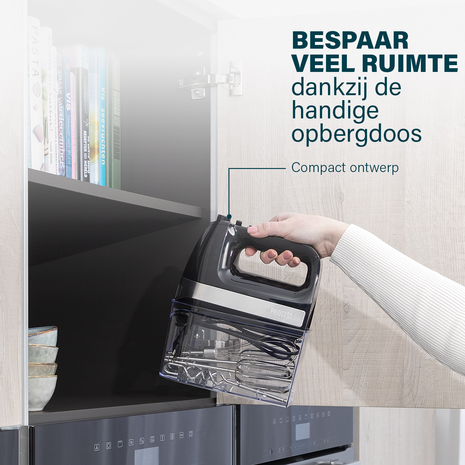 A hand holds a black Princess mixer in a clear case. It is placed in a kitchen cupboard near books and bowls.