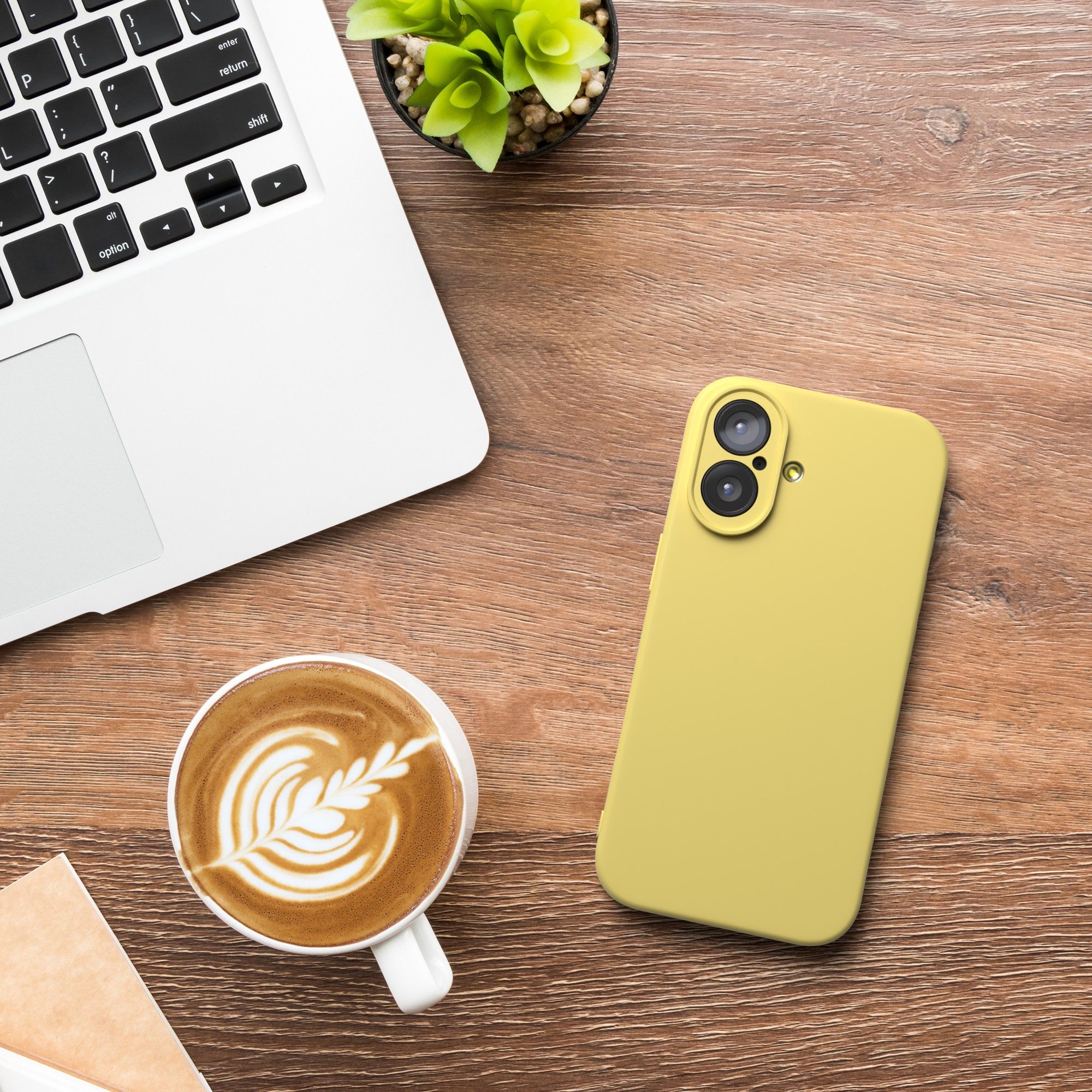 Ein Laptop, eine Tasse Kaffee und ein gelbes Telefon auf einer Holzoberfläche. Eine kleine Pflanze ist ebenfalls vorhanden.