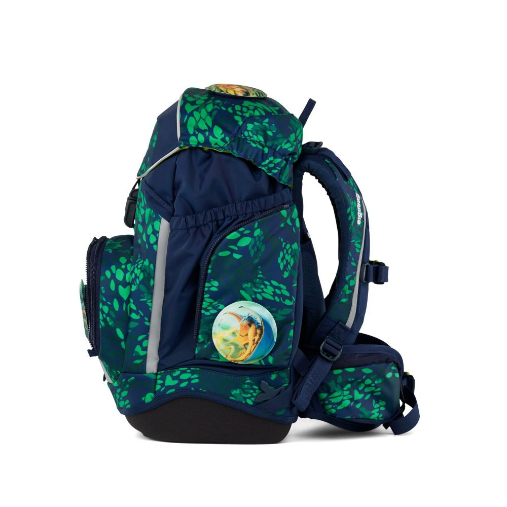 Ein Schulrucksack mit grünem Blättermuster auf marineblauem Hintergrund. Merkmale: runder Aufnäher und reflektierende Streifen.