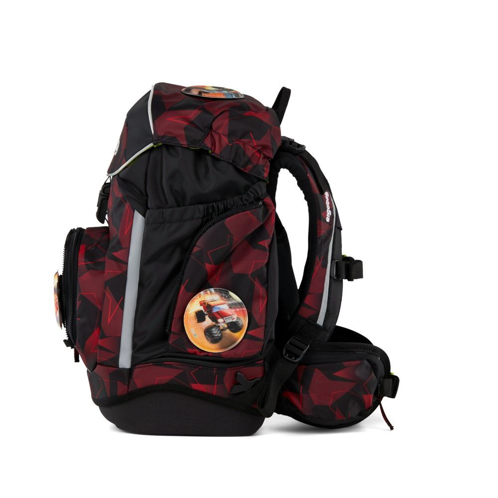 Ein schwarz-roter Rucksack mit einem Monster-Truck-Emblem. Er hat geometrische Muster und reflektierende Streifen.