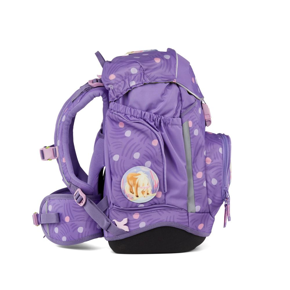 Lila Rucksack mit weißen und rosa Punkten, einem kleinen Pferdbild und schwarzem Boden. Träger und Reißverschlüsse sind sichtbar.