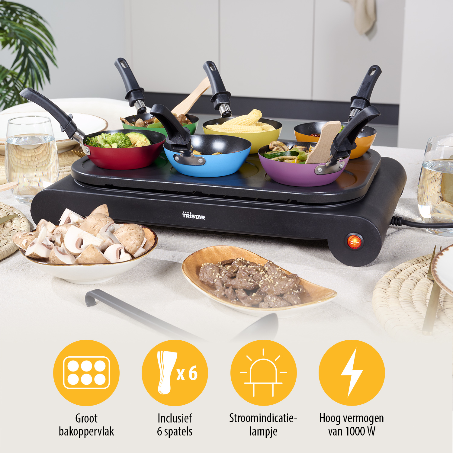 Ein Raclette-Grill mit sechs bunten Pfannen, gefüllt mit Gemüse. Zutaten und Utensilien stehen auf dem Tisch. Produktdetails werden unten angezeigt.