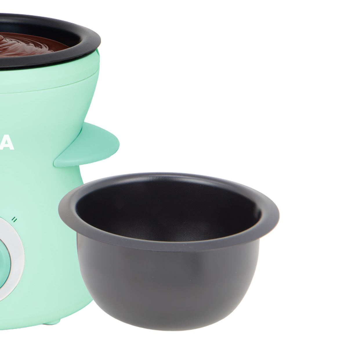 Una olla para derretir chocolate verde menta con un cuenco negro delante. La olla tiene chocolate dentro. Fondo blanco.